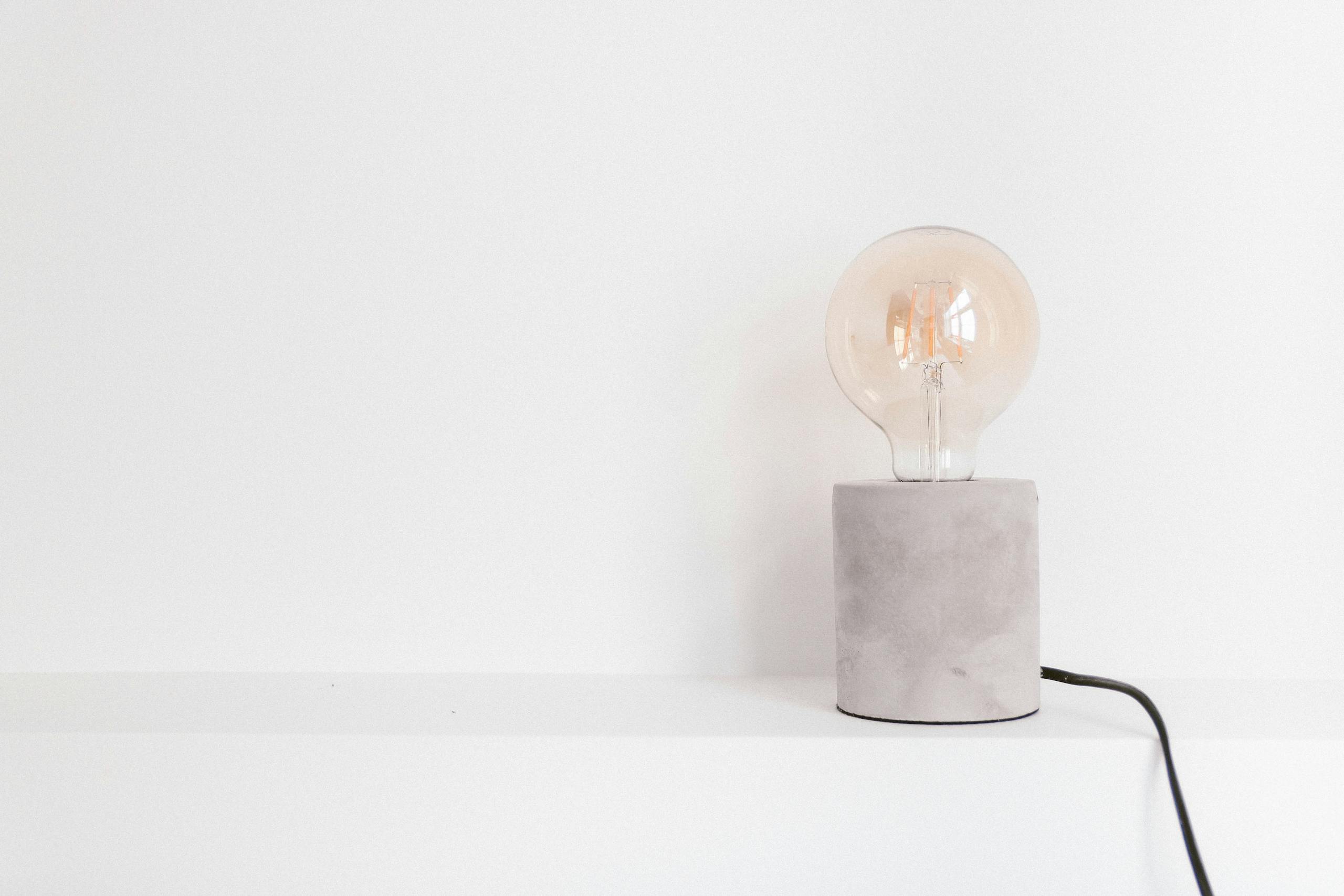 kadence templates - Close-up of an incandescent light bulb on a modern concrete base against a white background.