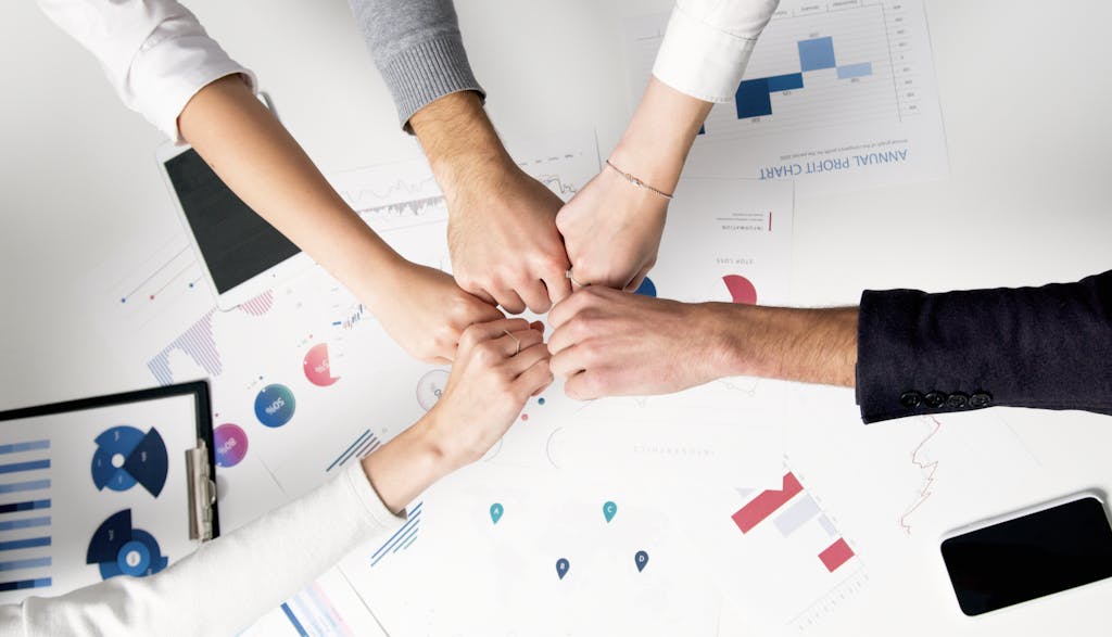 Essential WordPress Plugins - Colleagues celebrate success with a fist bump over finding and adding essential WordPress plugins depicting teamwork and unity.