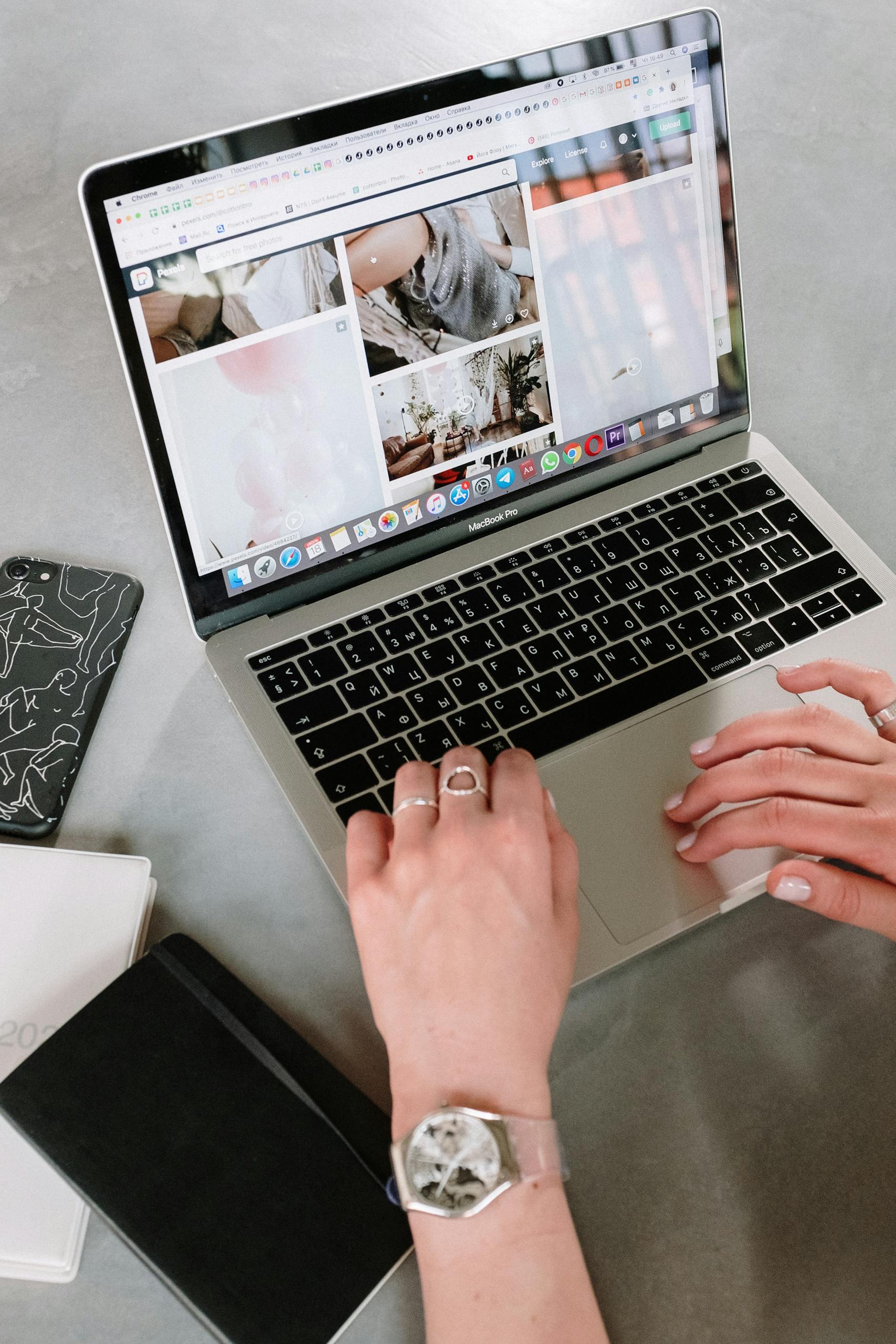 A close-up of a woman's hands browsing an online art gallery on a laptop.